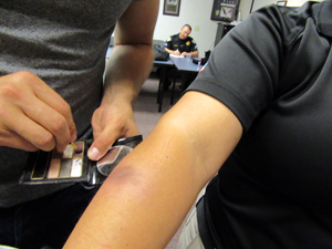 An officer applies makeup to simulate a bruise in a scenario on how to handle domestic violence cases
