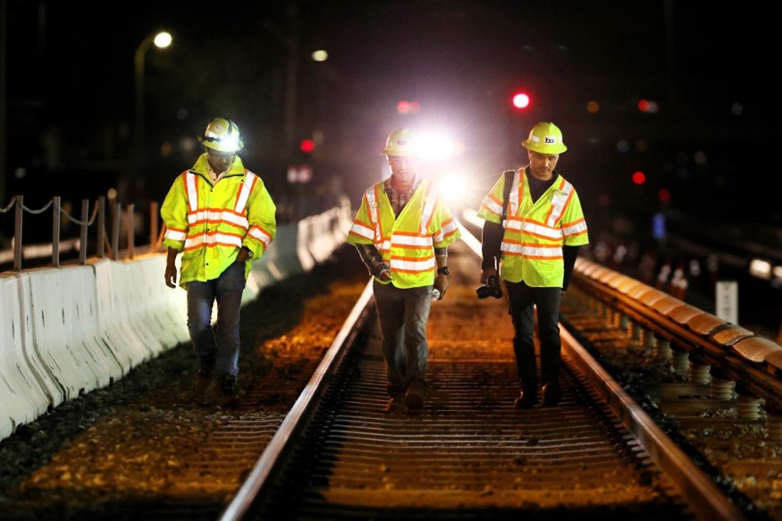 A trio of engineers walk along the BART tracks at night. 