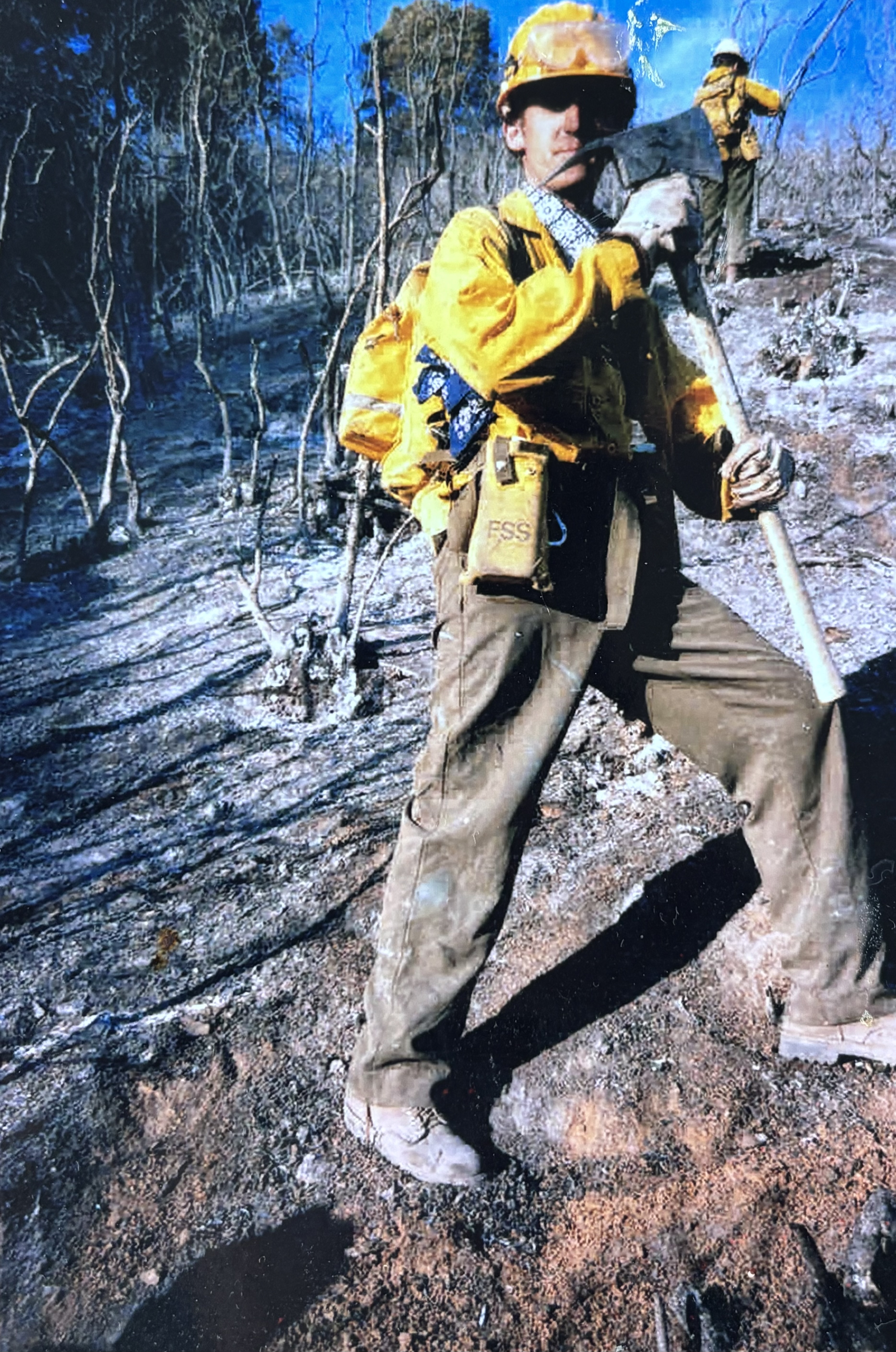 Bob Franklin is pictured on a burnt mountain holding an axe in firefighting gear