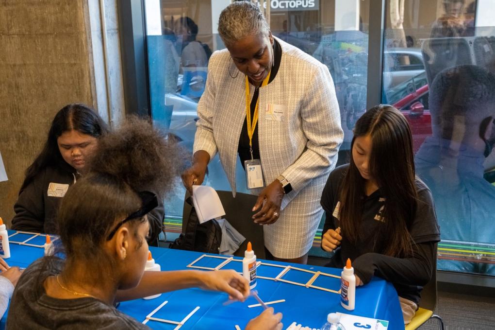 Tera Stokes-Hankins, Chief Transportation Officer at BART, assists attendees in building popsicle stick bridges during the Girls in Motion Fall 2023 Summit, hosted at BART Headquarters on Thursday, Oct. 19, 2023. Photo courtesy of Conner L’Hommedieu of Kimley-Horn. 