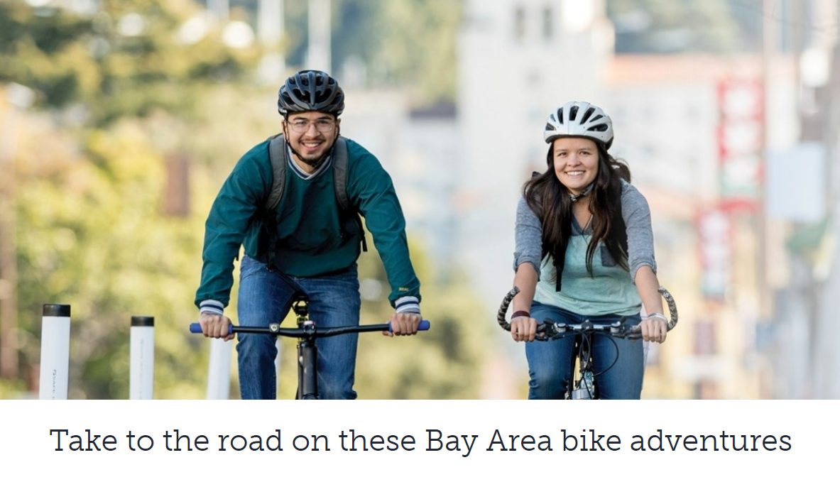 Two people smiling on bikes;