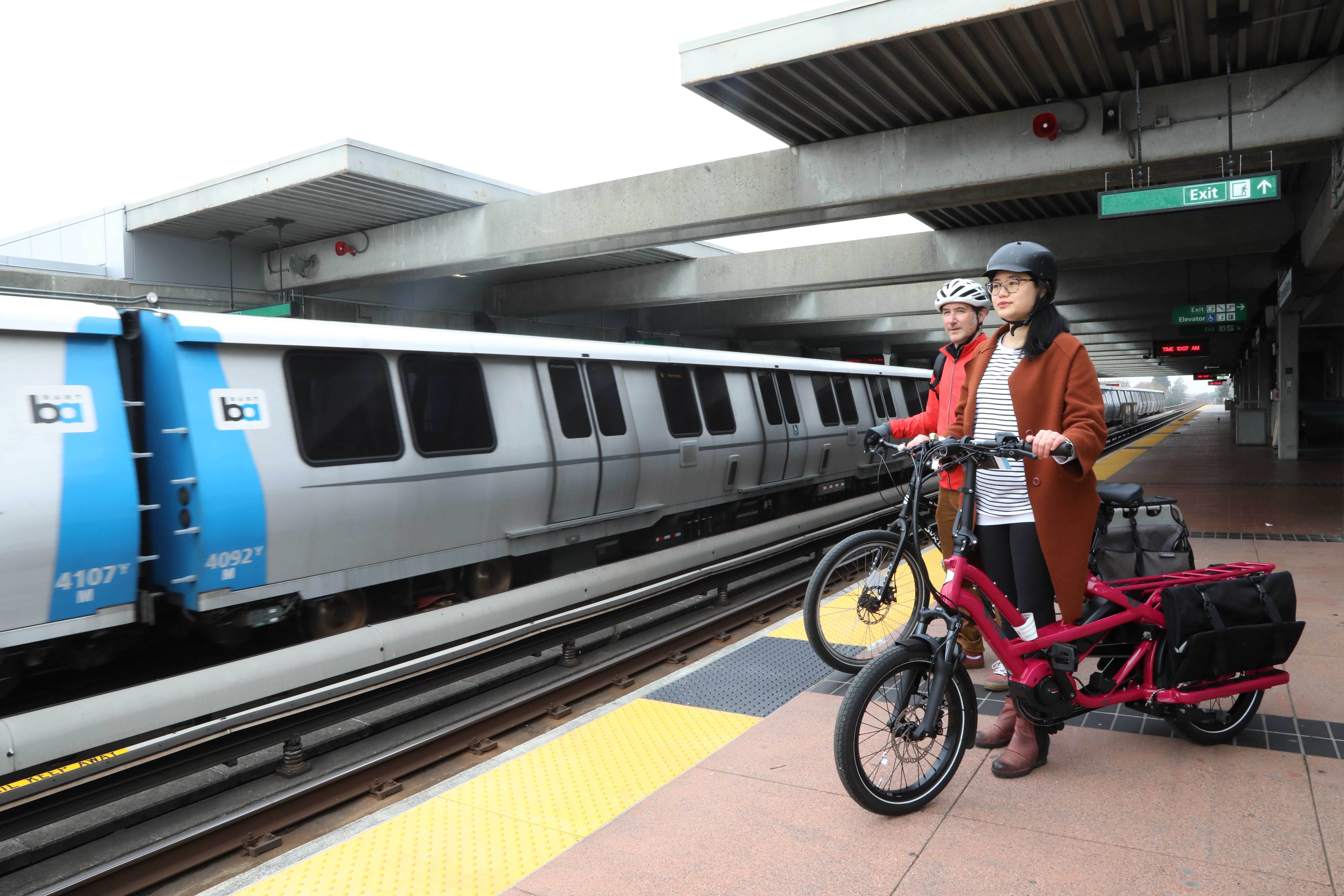 A woman and man on the BART platform with cargo bikes