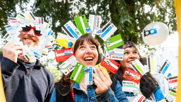 People smiling with paper ticket wreaths at SweaterFest