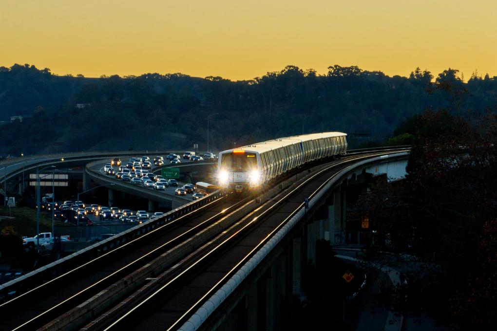 A BART train with car traffic in the background