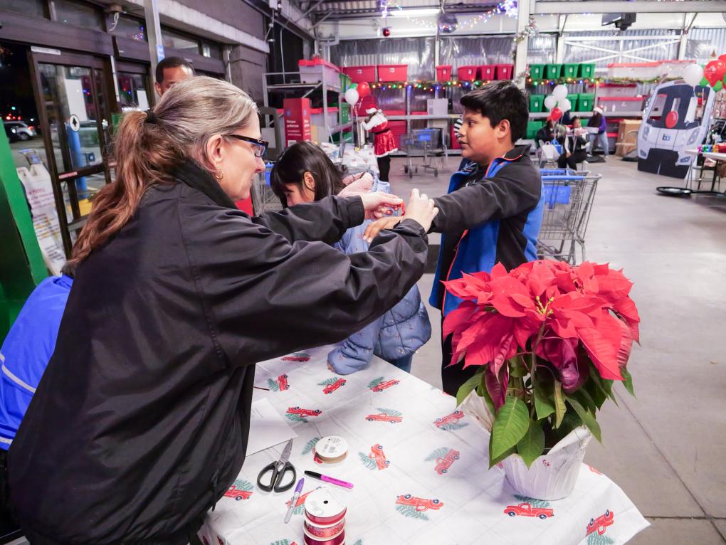 BART staff with participants of Shop with a Cop with holiday decor in the background.